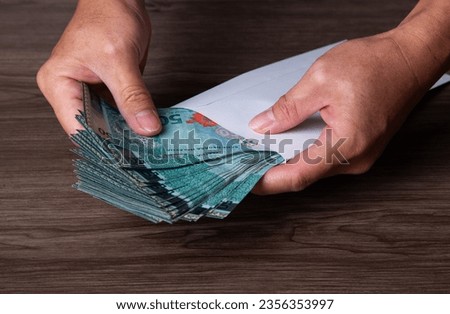Hand put a banknote into envelope. Bribery and corruption concept