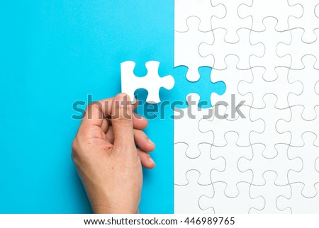 Hand put the last piece of jigsaw puzzle to complete the mission