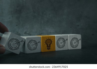 Hand put wooden cube with dart board icon to a bright light icon arrow it brainstorming, cooperation, teamwork, coworker for target or goal concept - Shutterstock ID 2364917025