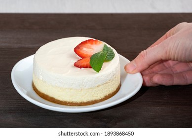 Hand Puts Plate Of Cheesecake On The Table