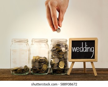 hand putting a coin into glass bottle, saving concept and a mini blackboard with text wedding - Shutterstock ID 588938672