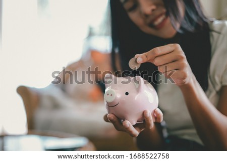 Woman​ hand putting coin into piggy bank, Finance or Savings concept.