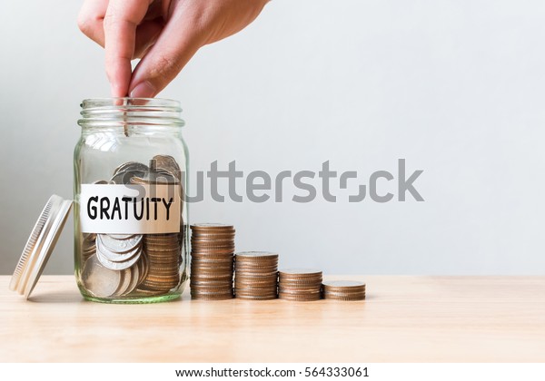 Hand putting coin in jar\
word gratuity with money stack, Concept business finance and\
investment