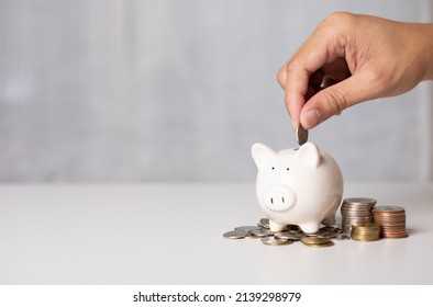 Hand putting a coin on pig saving. a pile of coins, business, investment, finance, and Money Saving for the future concepts. - Shutterstock ID 2139298979