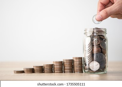 Hand putting coin to saving jar and coins stacking. Money saving investment profit and dividends concept. - Shutterstock ID 1735505111
