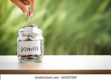 Hand putting Coins in glass jar for giving and donation concept - Shutterstock ID 655337509