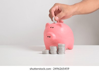 Hand putting coins into piggy bank isolated on white background. Business finance, savings and investment concept. hand putting coins into piggy bank to save money - Powered by Shutterstock