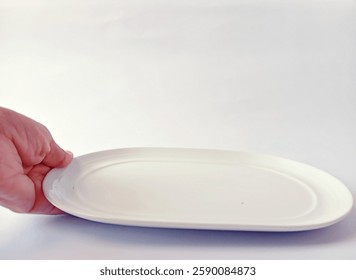 A hand putting down an empty white plate on a white background.