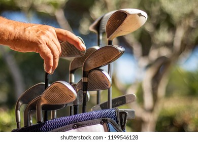 Hand Putting A Golf Iron In A Golf Bag