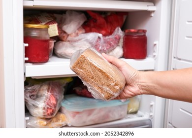 A Hand Putting Loaf Of Brown Bread In Reserve On A Shelf Of A Home Freezer, Long Life Food Storage Concept