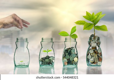 Hand putting mix coins and seed in clear bottle on cityscape photo blurred cityscape background,Business investment growth concept
