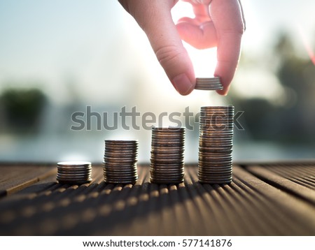 Hand putting money coins stack growing, saving money for purpose concept