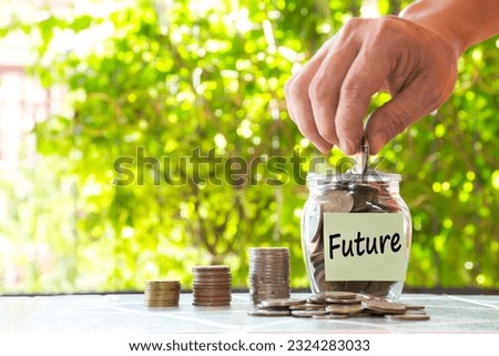 Hand putting money in glass jar and coin stack word Future paper note.
Concept Future money by managing their finances properly.