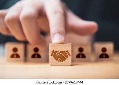 Hand putting hand shaking which print screen on wooden cube block  in front of human icon for business deal and agreement concept.