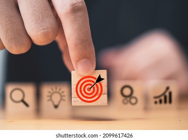 Hand  putting target board which printing on wooden cube block on mechanical gear and lightbulb icon  for creative and set up business objective target  goal concept. - Shutterstock ID 2099617426