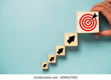 Hand putting virtual target board and arrow which print screen on wooden cube. Business achievement goal and objective target concept. - Shutterstock ID 2099617432