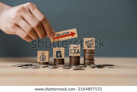 Hand putting wooden cube and inflation word a on coins in idea for FED consider interest rate hike, world economics, and inflation control, US dollar inflation