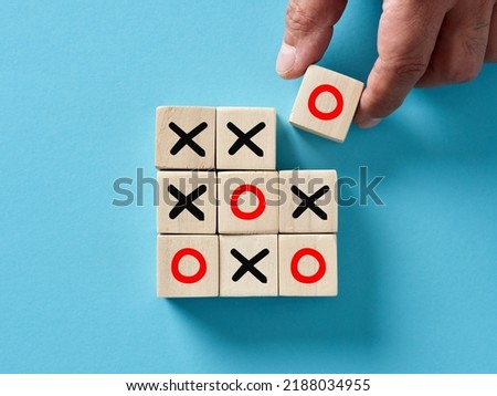 Hand putting wooden cube with O letter and win the x o or tic tac toe game. Business successful winning strategy.