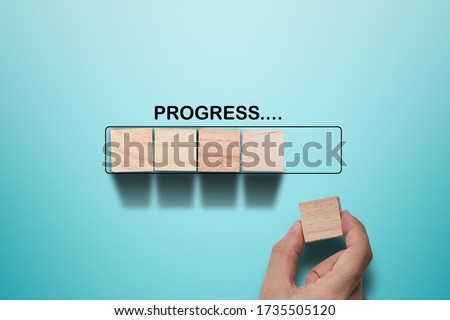 Hand putting wooden cube on virtual infographic rectangle block with progress wording. Job progressive concept.