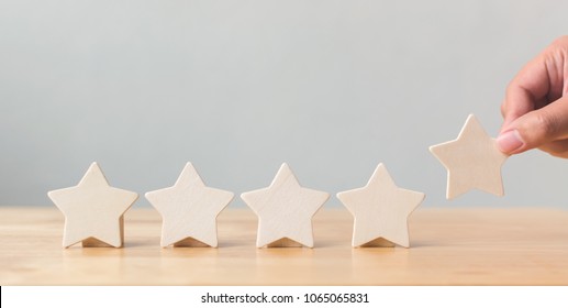 Hand putting wooden five star shape on table. The best excellent business services rating customer experience concept