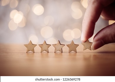 Hand putting wooden five star shape on table. The best excellent business services rating customer experience concept.
