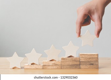 Hand putting wooden five star shape on table. The best excellent business services rating customer experience concept - Shutterstock ID 1329032360