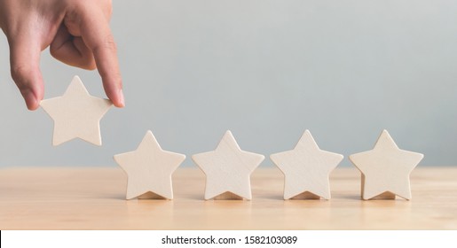 Hand Putting Wooden Five Star Shape On Table. The Best Excellent Business Services Rating Customer Experience Concept