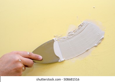 Hand With Putty Knife Repair Damaged Wall