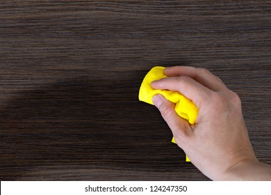 hand with a rag to dust the wood furniture