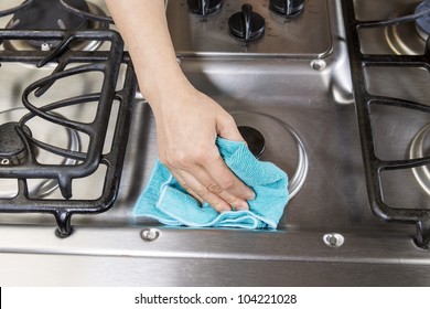 Hand With Rag Wiping Down Stainless Steel Stove Top Range