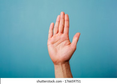 Hand raised against a blue background - Shutterstock ID 176659751