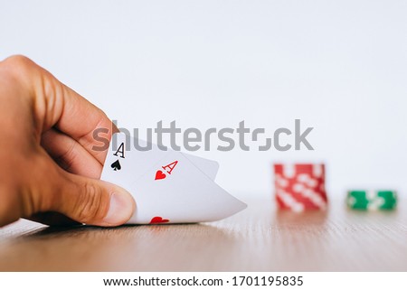 
Hand raising a pocket pair of aces in poker on the background of chips