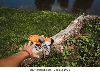 The hand reaches for a backpack lying on a log, hiking equipment, trekking in the forest. High quality photo - Powered by Shutterstock