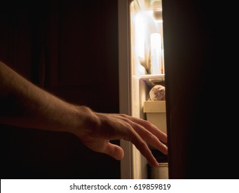 A Hand Reaches For The Fridge At Night