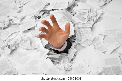 Hand reaches out from big heap of crumpled papers