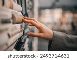 A hand reaches out to touch the spine of a book in a bookshelf, the rest of the bookstore is blurred out in the background.