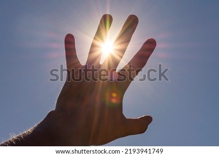 hand reaches for the sun. hand blocks the sun. High quality photo