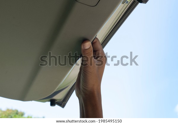 Hand reaching for the back door of the car to\
close it. under view of blue\
sky.