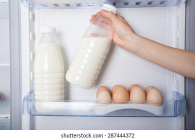 Hand Reaching For Bottle Of Milk In Refrigerator