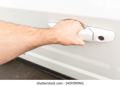 Hand Reaching For A Car Door Handle With A Key Hole On A White Vehicle