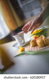 Hand reaching for a coffee, easter tulips and coffee on white planks, theme decoration