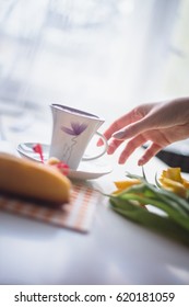 Hand reaching for a coffee, easter tulips and coffee on white planks, theme decoration