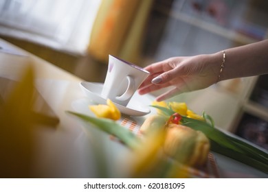Hand reaching for a coffee, easter tulips and coffee on white planks, theme decoration