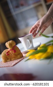 Hand reaching for a coffee, easter tulips and coffee on white planks, theme decoration