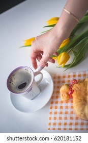 Hand reaching for a coffee, easter tulips and coffee on white planks, theme decoration