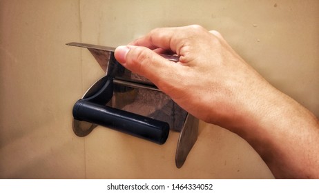 a hand reaching for empty paper roll in toilet