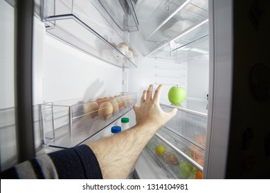 Hand Reaching For A Green Apple In An Open Refrigerator