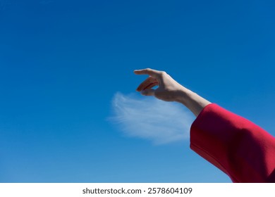 Hand reaching up into the sky, with a cloud in the background. Scene is peaceful and serene, as if the person is reaching for something beyond their grasp