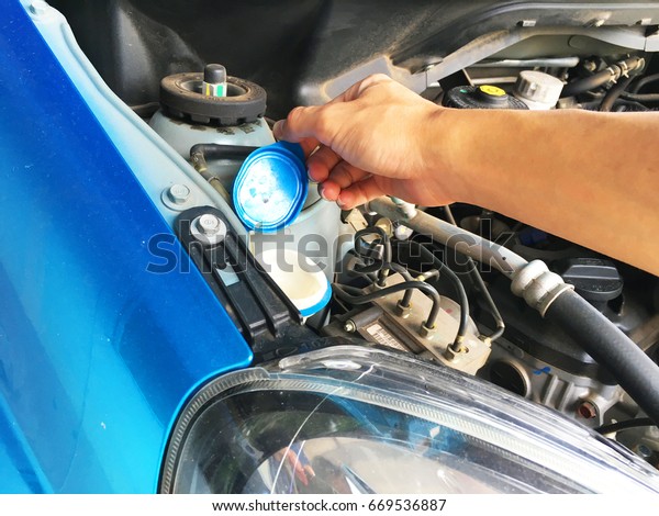 hand Reaching to open the tank\'s lid of water\
for injection car\
windshield.