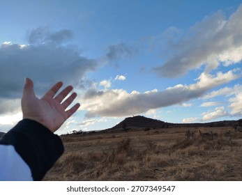 Hand Reaching for the Sky Dramatic over an Arid and Desolate Landscape.
